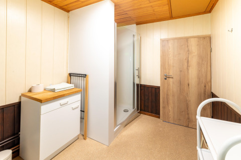 Moderne badkamer in Les Bouleaux lodge in België met douche, houten plafond en houten deur.