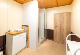 Moderne badkamer in Les Bouleaux lodge in België met douche, houten plafond en houten deur.