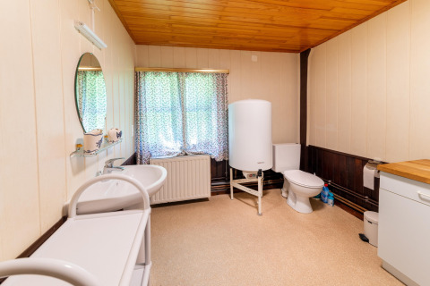 Badkamer in lodge «Les Bouleaux» in België met wastafel, toilet, boiler en opbergkast.