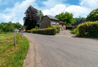 Straatbeeld met stenen lodge en groene heggen bij Les Bouleaux, gelegen in het landelijke België.