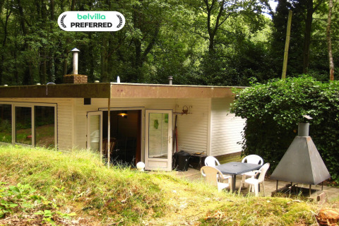 Lodge chaleureux The Deer Forest avec terrasse, mobilier de jardin et barbecue en pleine forêt verdoyante.