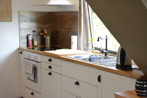 Moderne keuken met witte kasten, fornuis, gootsteen en raam in chalet Mise Au Vert in België.