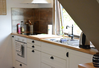 Moderne køkken med hvidt skab, komfur, håndvask og vindue i et chalet i Belgien, Mise Au Vert.