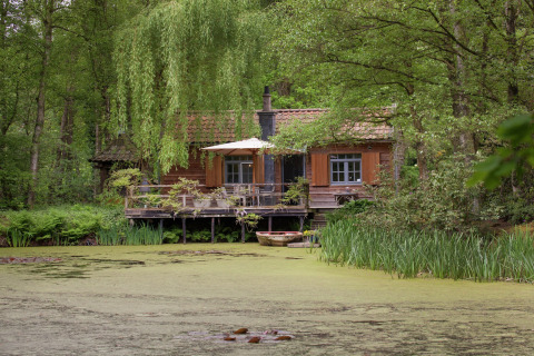 Een charmant houten huisje The Wijerschans aan een vijver, omringd door bos en groene natuur.