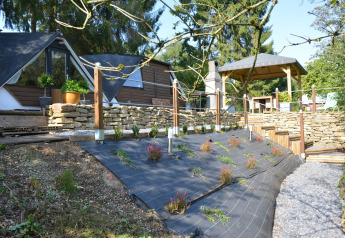 Chalet 'Mise Au Vert' i Belgien med moderne sorte telte, stenmure og beplantning på en skråning.
