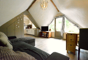 Heller Dachwohnraum im Chalet 'Mise Au Vert' in Belgien mit Sofa, TV, Essbereich und Gartenblick.