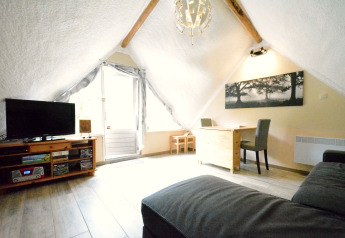 Helles Wohnzimmer im Chalet Mise Au Vert in Belgien mit Schräge, TV, Sofa, Schreibtisch und Fenster.