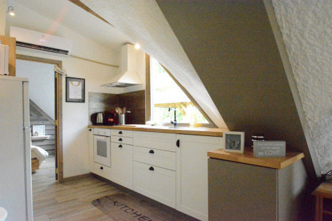 Knusse keuken in chalet ‘Mise Au Vert’ in België met schuine plafonds en moderne inrichting.