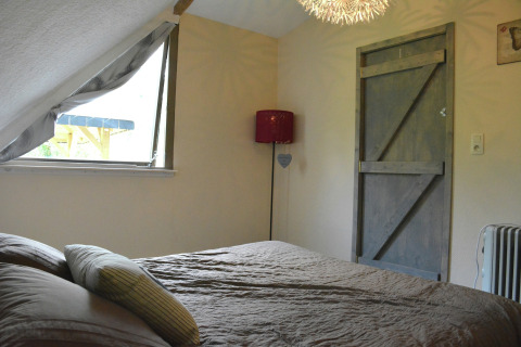 Slaapkamer met schuin plafond, rustieke deur en raam in chalet 