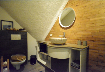 Modernes Badezimmer im Chalet Mise Au Vert, Belgien, mit Holz- und Steinwänden, Waschbecken und Spiegel.