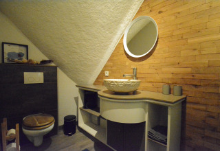 Moderne badkamer in Chalet Mise Au Vert, België, met houten accenten, wasbak, spiegel en toilet.