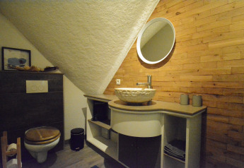 Et moderne badeværelse i træ og sten i Chalet Mise Au Vert i Belgien, med vask, spejl og toilet.
