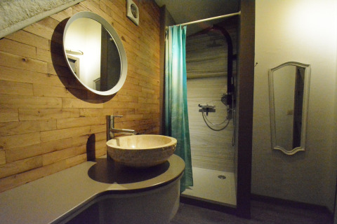 Moderne badkamer in chalet Mise Au Vert in België met houten wanden, ronde spiegel en inloopdouche.