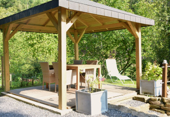 Überdachte Terrasse mit Esstisch und Stühlen in grüner Umgebung beim Chalet 'Mise Au Vert' in Belgien.