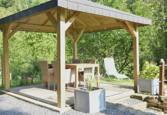 Udendørs lysthus med spisebord og stole i naturlige omgivelser ved chalet 'Mise Au Vert' i Belgien.