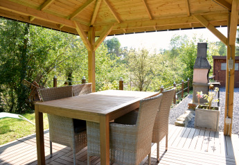 Essbereich im Freien unter einem Holzpavillon beim Chalet Mise Au Vert in Belgien mit Blick ins Grüne.