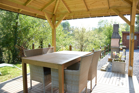 Buiten eethoek onder houten prieel bij chalet Mise Au Vert in België, met zicht op tuin en barbecue.