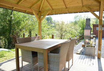 Udendørs spiseområde under en træpavillon ved chalet Mise Au Vert i Belgien med udsigt til naturen.