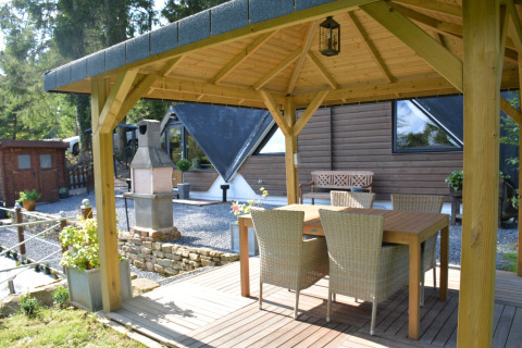 Overdekt terras bij chalet 'Mise Au Vert' in België met een houten tafel en vier rotanstoelen.