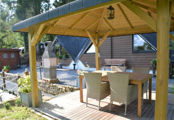 Udsigt fra en overdækket terrasse ved chalet 'Mise Au Vert' i Belgien med bord og fire stole.