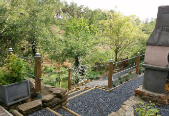 Gartenweg mit Kies und Geländer bei Chalet „Mise Au Vert“ in Belgien, umgeben von Bäumen und Grün.