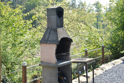 Buitenbarbecue met schoorsteen bij chalet 'Mise Au Vert' in België, omringd door groene natuur.