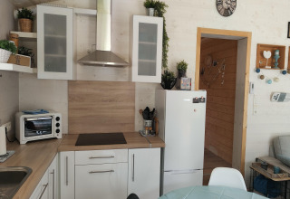 Moderne keuken bij Chatillon 67 in België, met witte kasten, koelkast, oven en groene planten.