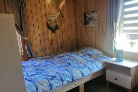 Gezellige slaapkamer met houten wanden, een tweepersoonsbed en blauwe dekbed bij Chatillon 67, België.