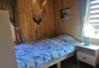 Gezellige slaapkamer met houten wanden, een tweepersoonsbed en blauwe dekbed bij Chatillon 67, België.