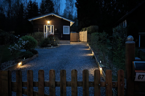 Ingang van de lodge bij Chatillon 67 in België met verlichte oprit en houten hek in de avond.