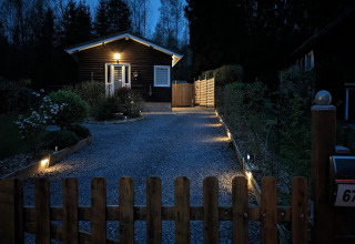 Ingang van de lodge bij Chatillon 67 in België met verlichte oprit en houten hek in de avond.
