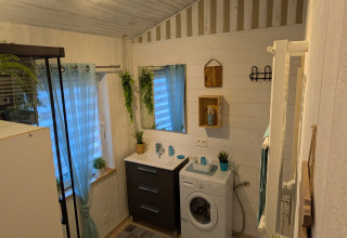 Modern en gezellig badkamer in Chatillon 67 lodge in België met wasmachine, planten en een grote spiegel.