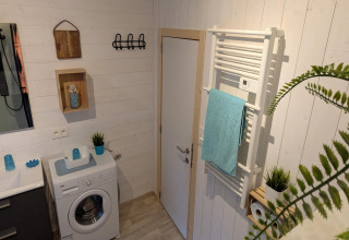 Moderne badkamer in lodge Chatillon 67 in België met wasmachine, handdoekradiator en planten.