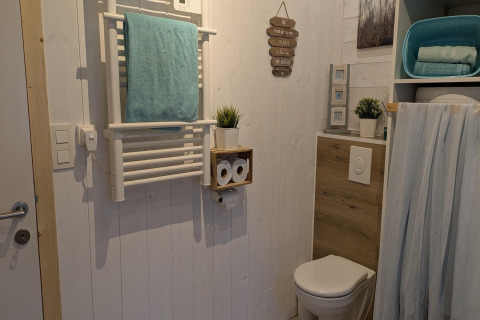 Moderne badkamer in Chatillon 67, België, met toilet, handdoekverwarmer en houten decoratie.
