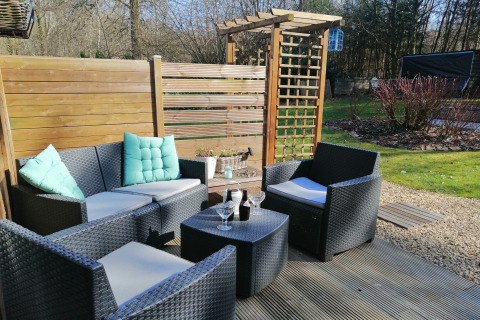 Buiten zithoek bij lodge Chatillon 67 in België met rotanmeubels en houten afscheidingen.