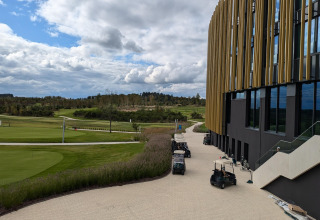 Uitzicht vanaf Chatillon 67 lodge in België met golfkarretjes, groene velden en een modern gebouw.