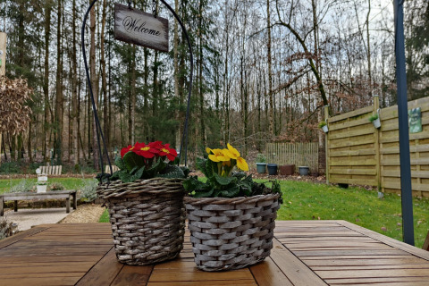 Twee gevlochten bloempotten met bloemen op een houten tafel bij een lodge in Chatillon 67, België.