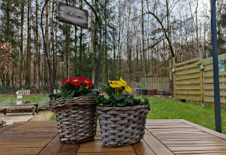 Twee gevlochten bloempotten met bloemen op een houten tafel bij een lodge in Chatillon 67, België.