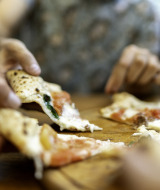 Close-up of people sharing and enjoying pizza at Camping Centro Vacanze San Marino in San Marino, Italy.
