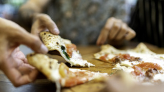 Close-up of people sharing and enjoying pizza at Camping Centro Vacanze San Marino in San Marino, Italy.