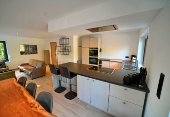 Cucina moderna e soggiorno open space nello chalet «DES BOIS», una lodge accogliente in Belgio.