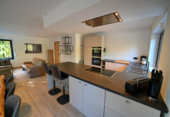 Zona cucina e soggiorno moderna e open space nel Chalet «DES BOIS» in Belgio con arredo elegante.