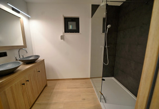 Moderne badeværelse i Chalet «DES BOIS» i Belgien med dobbelt vask, træskabe og stor bruseniche.