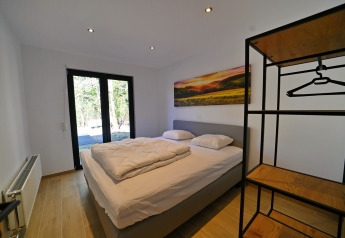 Camera moderna nello Chalet «DES BOIS» in Belgio con letto matrimoniale, quadro e vista sulla natura.