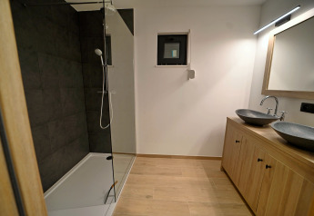 Bagno moderno al Chalet «DES BOIS» in Belgio con doppi lavabi, mobili in legno e ampia doccia.