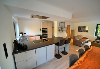 Moderna cucina open space e zona soggiorno al Chalet «DES BOIS» in Belgio, ambiente luminoso ed elegante.