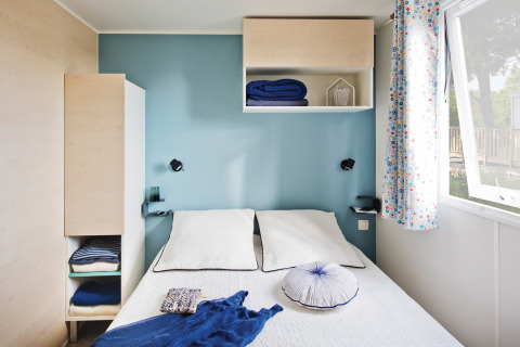 Chambre lumineuse au chalet 'Vlaamse gaai' en Belgique avec lit double, mur bleu et fenêtre ouverte.