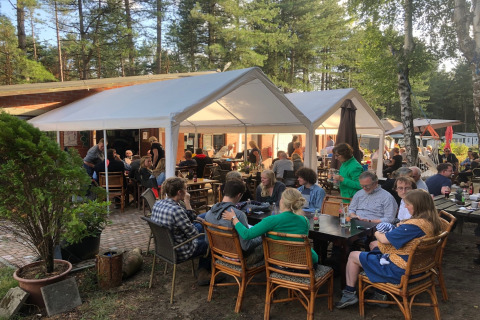 Terrasse extérieure du chalet « Vlaamse gaai » en Belgique, des convives dînent sous des tentes blanches.