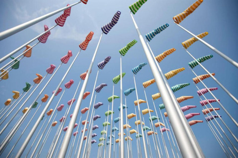 Maniche a vento colorate su pali sotto il cielo blu in una struttura glamping, viste dal basso.