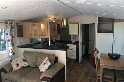 Zona soggiorno e cucina dello chalet Koperwiek in Belgio, divano beige e cucina moderna con arredo chiaro.
